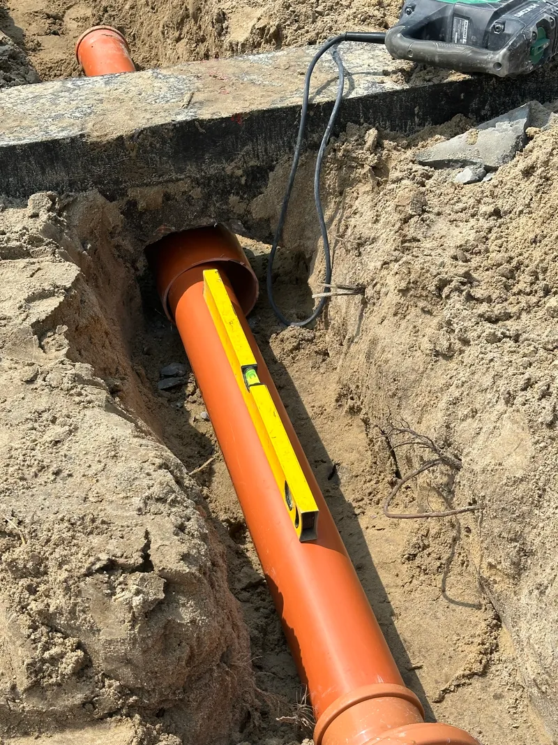 Sprawdzanie spadku poziomicą na rurze kanalizacyjnej